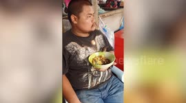 Bird joins Thai man in enjoying a bowl of noodles