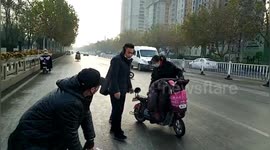 Dozen of bikers slip down on icy road as water sprayed from sprinkler truck freeze on road in China