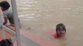 Children play in floodwater after heavy rain in southern Thailand