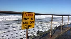 Coast Guard flies over “caution: waves may break over seawall” sign near where man was swept away