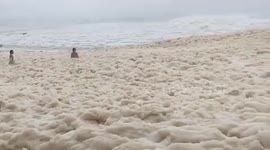 Beachgoers enjoy sea foam brought by storm weather on the beaches of Australia