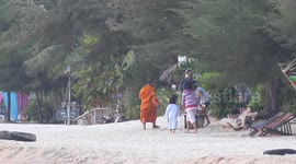 A Buddhist monk collects alms on a beach in Thailand.