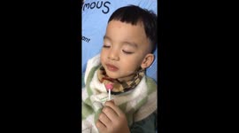 The funny boy was sleepy while eating the lollipop candy