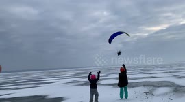 Moment paraglider swoops over frozen Lake Champlain in Canada
