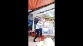 The man balances the knife with his mouth with the ball and glasses of water above