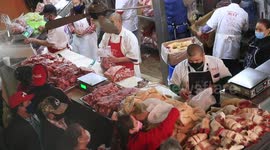 A butcher cuts a head of beef in one of the shops of the Municipal Market during food sales for the New Year's dinner