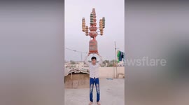 Boy displays his extreme balancing skill by balancing a heavy metal cylinder on the top of his head in Northern India