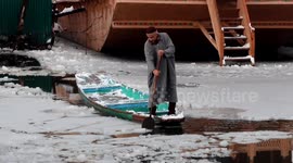 Local boatman force their way across frozen lake after heavy snowfall in Kashmir