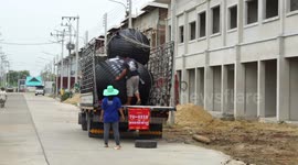 Plastic septic tanks being unloaded from a truck, at a building site in Thailand.