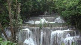 Autumn leaves falling in a refreshing breeze at a stunning waterfall in Thailand.