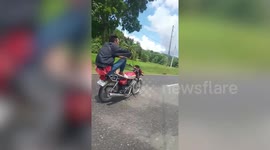 Filipino man sits at back of motorcycle to drive along road without hands