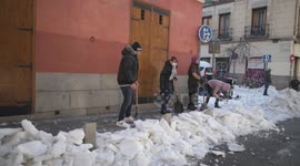 Residents armed with shovels begin to clear snow and ice off Madrid roads