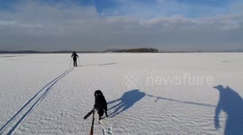 This incredible footage shows a 57-year-old man on skis being pulled across a snow-covered sandy beach by his pet pooch
