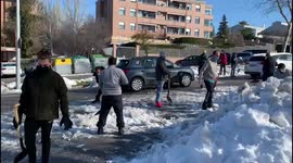 Families armed with shovels clear snow and ice outside school in Madrid
