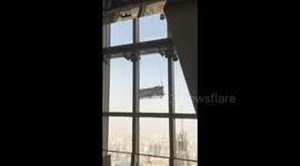 Window cleaners swing from China's second-tallest building