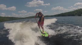 Boy dribbles hockey ball while wakesurfing in Canada
