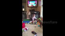 Cute baby waves and falls into box of diapers