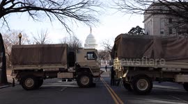 U.S. Capitol Dome seen from behind National Guard trucks and with flag at half-staff on eve of presidential inaugural
