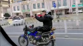 Chinese man does 'arm dance' while driving motorcycle along road