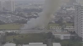 Grass fire sends smoke into the air next to Toyota centre in Bangkok, Thailand