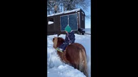 Sweet little 2 years old enjoys time on her pony in the snowy countryside!