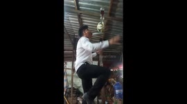 Vietnamese man balances football and glasses of water on knife held in his mouth