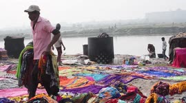 Open-air laundrette set up on banks of polluted river on outskirts of Delhi
