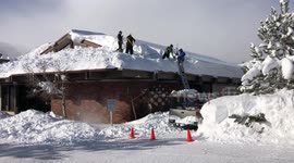 Snow being removed from rooftop of building
