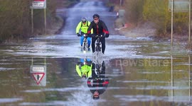 Cyclists brave chilly floodwaters on submerged UK road
