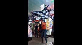 Vietnamese woman balances motorcycle on head while dancing to music