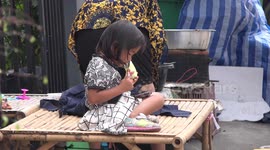 A cute kid playing with a smart phone and eating at the same time, she has her hands full.