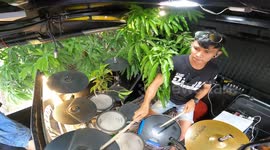 Drummer dodges tree branches poking through window of mobile music bus