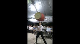 Vietnamese man plays giant drum that is balanced on his head