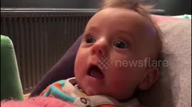 Baby laughs in astonishment as mum eats biscuit