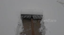 First-person view of shovel clearing snow from driveway.