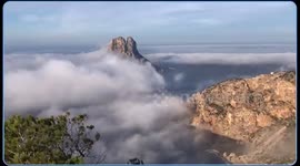 Incredible waves of mist surfing in the Mediterranean Sea on the island of es Vedrá.