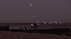 February's full Snow Moon seen from Whitstable beach, Kent early morning.