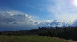Time lapse of low clouds passing over park on windy day.