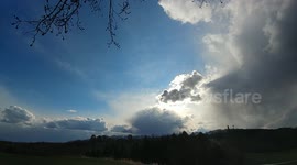 Time lapse of dark clouds passing over sun on windy day.
