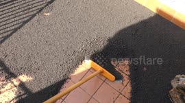 Sicilian resident sweeps layer of volcanic ash from his balcony after Mount Etna eruptions