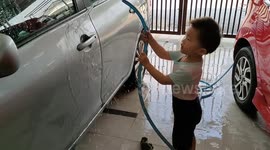Diligent 2-year-old toddler helps parents washing cars