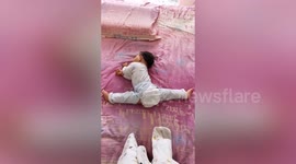 Toddler seen doing splits while sleeping in bed