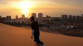 Watch as sandboarder glides down dunes in Chile with sunset backdrop