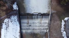 Sheet of ice on frozen US river slowly crumbles as it flows over waterfall