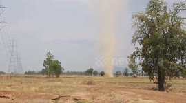 Dust devil tornado sweeps through field in Thailand