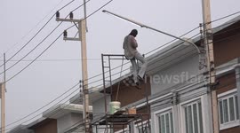 An electrician replacing light bulbs on a street while standing on scaffolding which is on a truck.