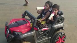 Don't drink and drive kids! Pair of toddlers drive across beach while sipping milk