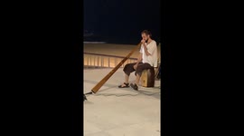 A man is performing on the street using a unique traditional instrument.