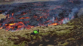 Local poses next to stream of lava spewing from Iceland volcano