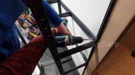 Son and dad mounting shelf in garage and screw in together